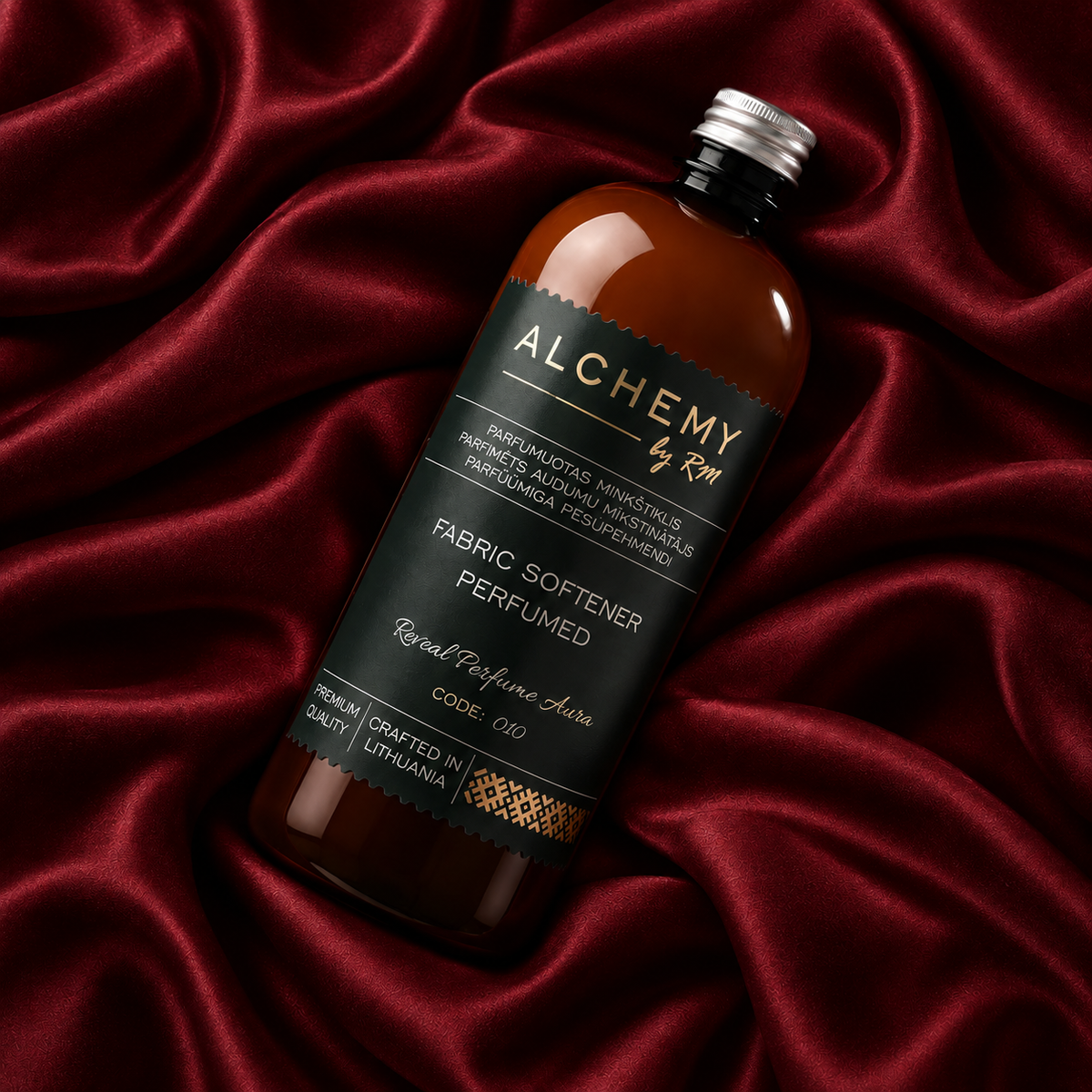 Parfumuotas audinių minkštiklis Alchemy by RM gintariniame butelyje ant bordo šilko